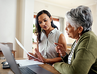 Two women looking at forms on the computer
