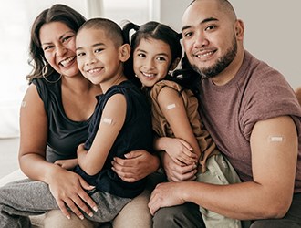 A recently-vaccinated family smiles at the camera.